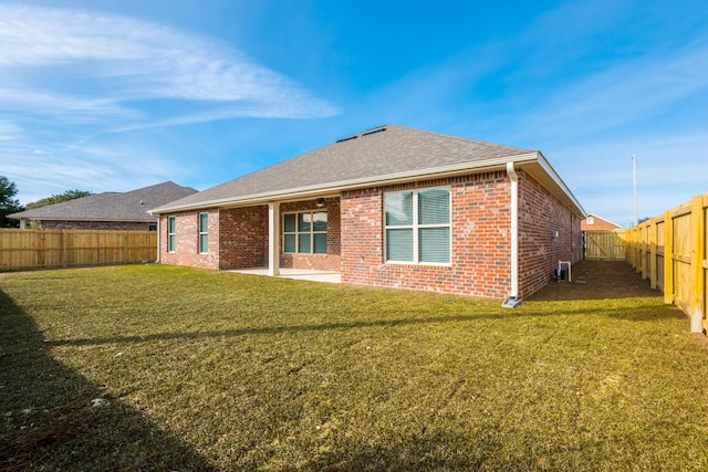 rear view of property featuring a patio, a fenced backyard, brick siding, a shingled roof, and a yard