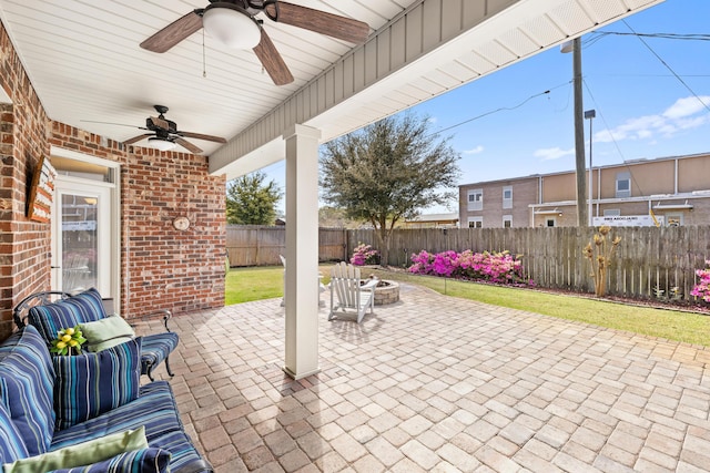 view of patio featuring a fenced backyard, ceiling fan, and an outdoor living space with a fire pit