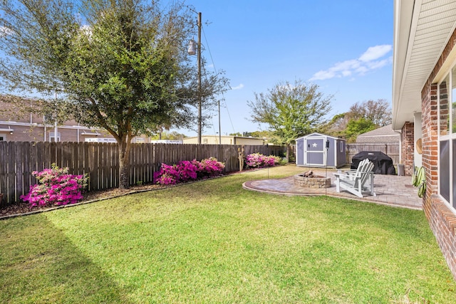 view of yard with a fenced backyard, a patio area, a fire pit, an outdoor structure, and a shed