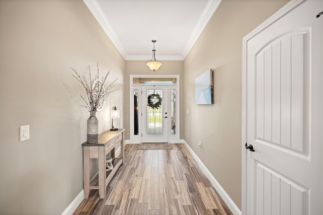 foyer featuring baseboards, ornamental molding, and wood finished floors