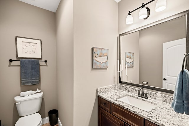bathroom featuring baseboards, toilet, and vanity