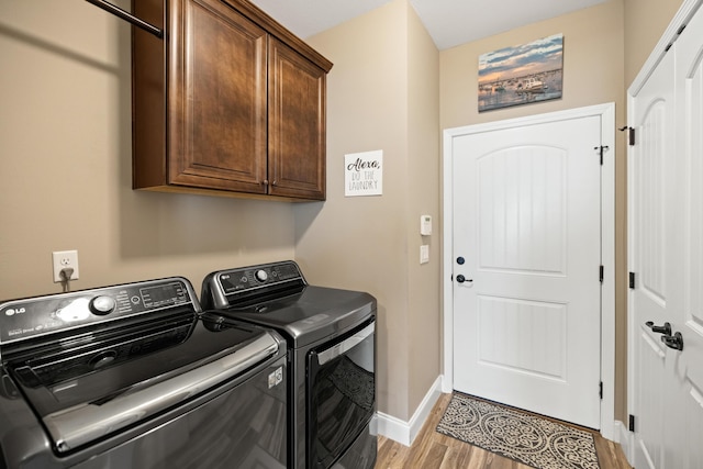 washroom featuring washing machine and clothes dryer, cabinet space, baseboards, and light wood finished floors