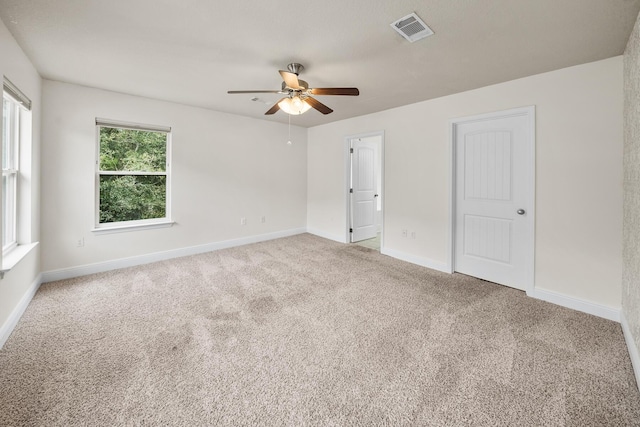 spare room featuring baseboards, carpet floors, ceiling fan, and visible vents