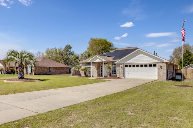 single story home with roof mounted solar panels, a garage, concrete driveway, a front yard, and brick siding