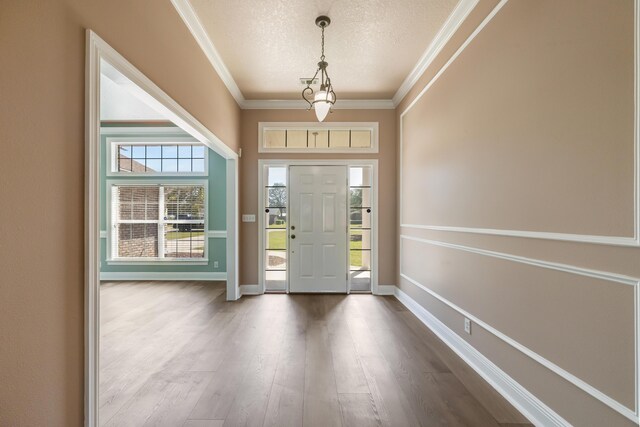 entrance foyer with ornamental molding, dark wood-style floors, baseboards, and a textured ceiling