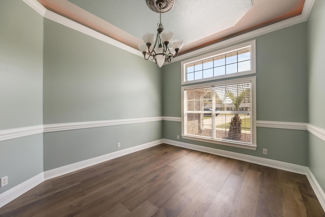 empty room featuring dark wood finished floors, baseboards, ornamental molding, and an inviting chandelier
