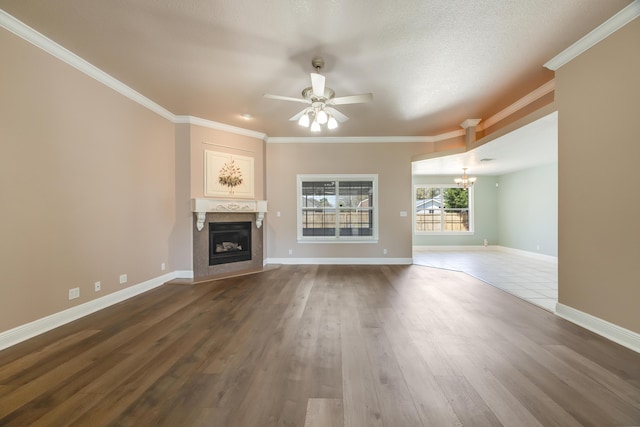 unfurnished living room featuring dark wood-style floors, a fireplace, ceiling fan with notable chandelier, and ornamental molding