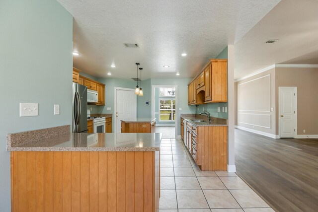 kitchen with visible vents, a peninsula, white appliances, a kitchen island, and light tile patterned floors