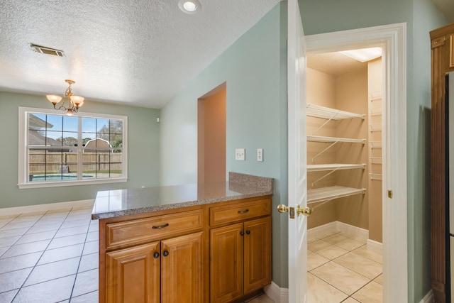 kitchen with a notable chandelier, visible vents, light tile patterned floors, and brown cabinets
