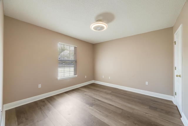 empty room with baseboards, dark wood-type flooring, and a textured ceiling