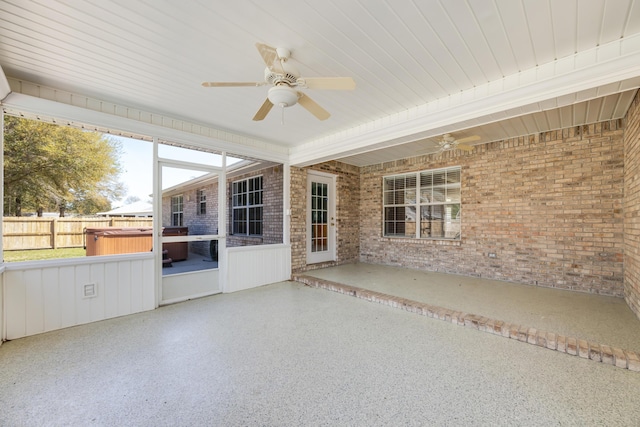 unfurnished sunroom featuring a ceiling fan and a jacuzzi