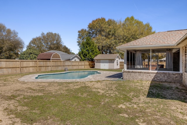 view of pool featuring a sunroom, a fenced in pool, a fenced backyard, a lawn, and an outbuilding