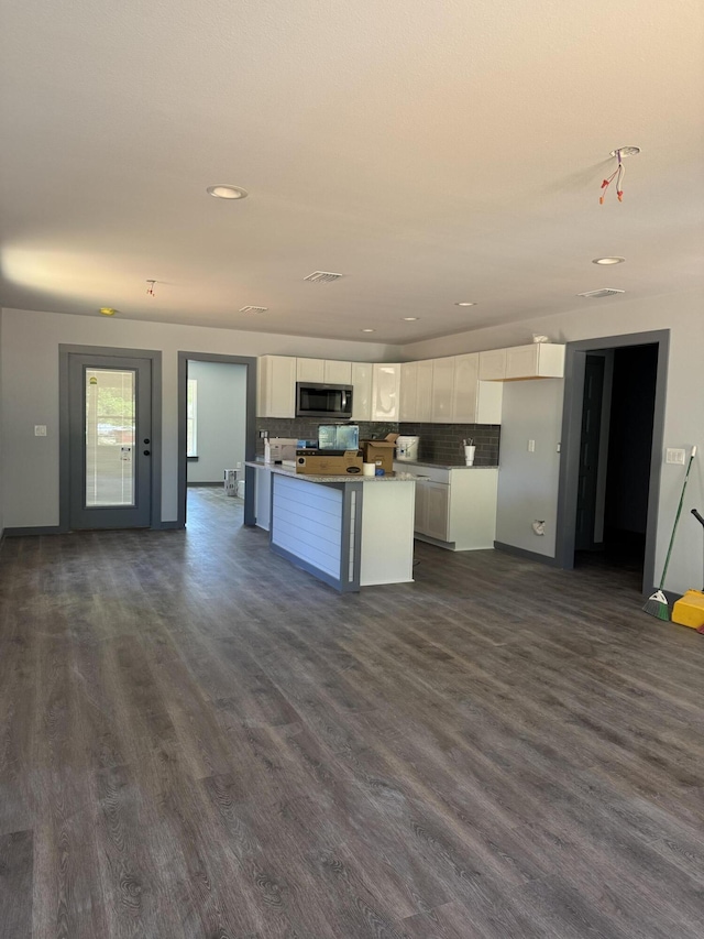 kitchen featuring recessed lighting, stainless steel microwave, white cabinets, dark wood-type flooring, and tasteful backsplash