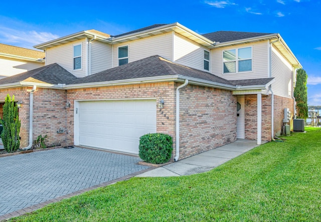 view of front of home featuring a front lawn, decorative driveway, central AC, roof with shingles, and an attached garage