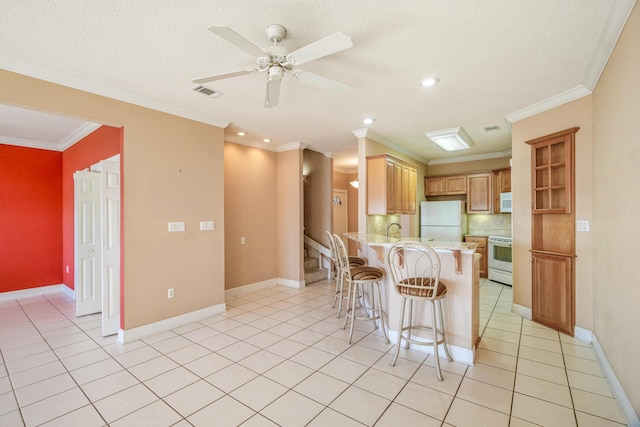 kitchen with visible vents, a kitchen breakfast bar, white appliances, a peninsula, and light tile patterned floors