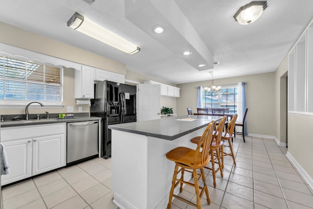 kitchen featuring a kitchen bar, a sink, dark countertops, and stainless steel dishwasher