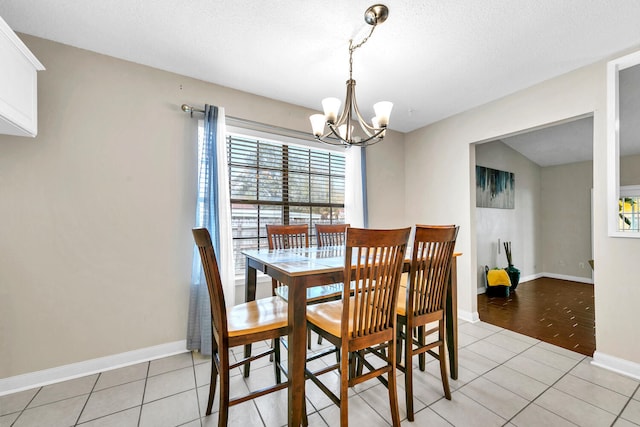 dining space featuring baseboards, a textured ceiling, a chandelier, and light tile patterned floors