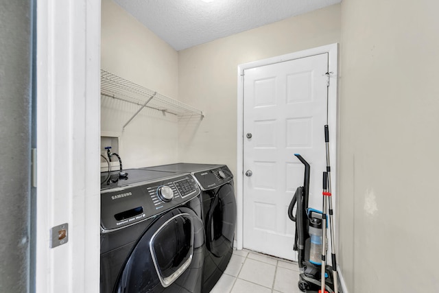 laundry room featuring light tile patterned flooring, washer and dryer, laundry area, and a textured ceiling