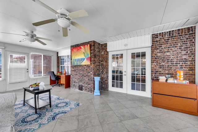 tiled living area with french doors, a ceiling fan, and brick wall