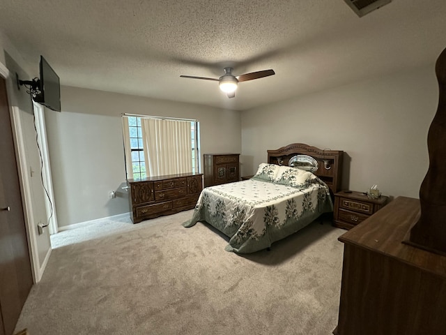 carpeted bedroom featuring a textured ceiling, visible vents, a ceiling fan, and baseboards