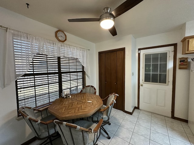 dining space with light tile patterned floors, a ceiling fan, and baseboards