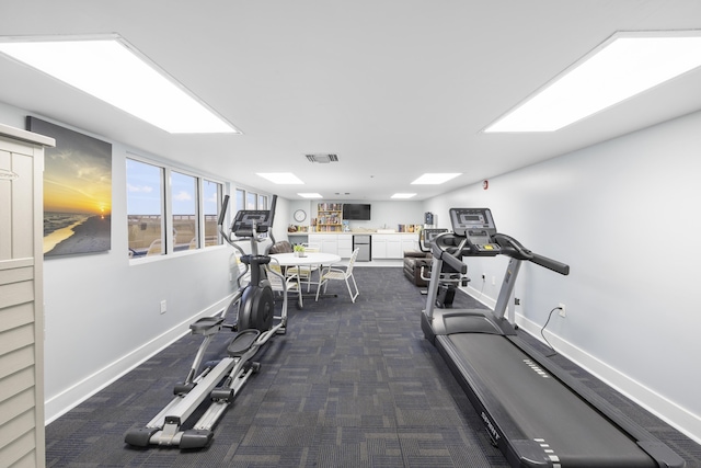 workout area featuring baseboards, visible vents, and dark colored carpet