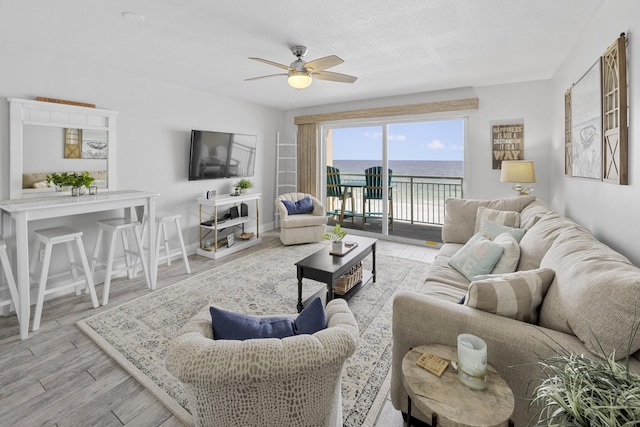 living room featuring baseboards, ceiling fan, and wood finished floors