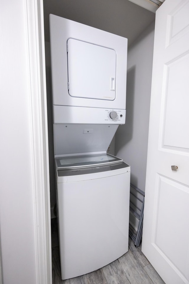 laundry area featuring light wood finished floors, laundry area, and stacked washer / drying machine