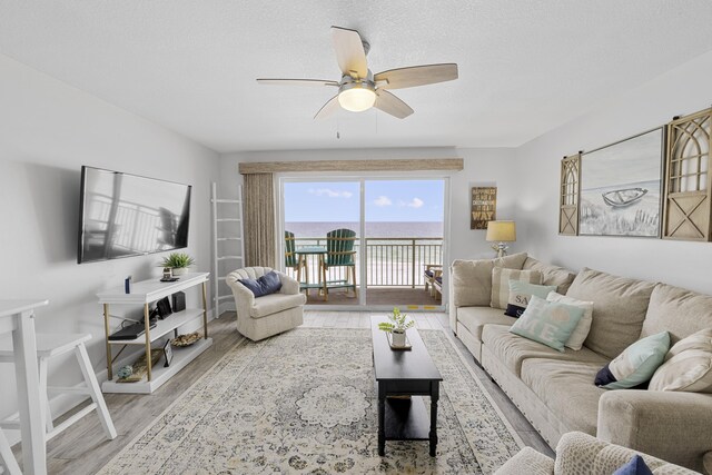 living area with a ceiling fan, a textured ceiling, baseboards, and wood finished floors