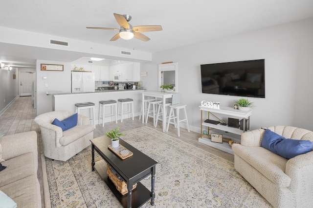 living area with light wood-style flooring, visible vents, and a ceiling fan