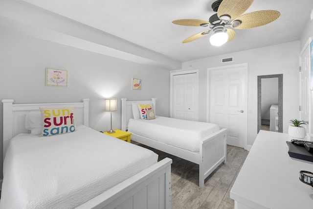 bedroom featuring light wood-type flooring, a ceiling fan, multiple closets, and visible vents