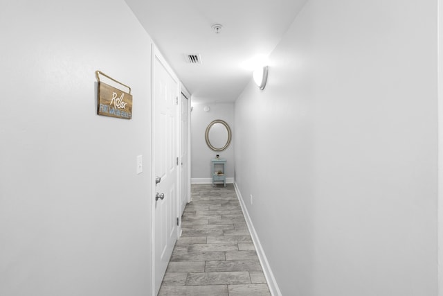 corridor with baseboards, visible vents, and light wood-style flooring