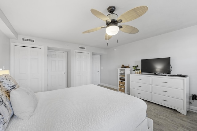 bedroom featuring baseboards, visible vents, multiple closets, and light wood-style floors