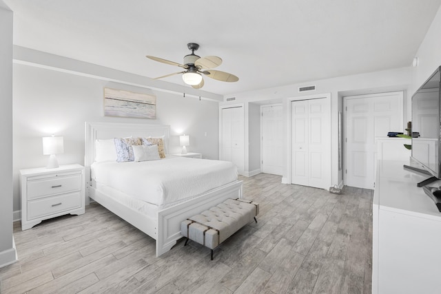 bedroom featuring multiple closets, ceiling fan, visible vents, and light wood-type flooring
