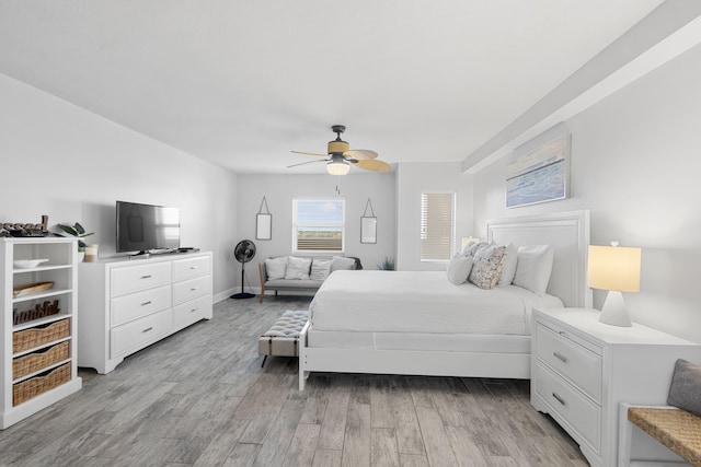 bedroom with light wood finished floors, baseboards, and ceiling fan