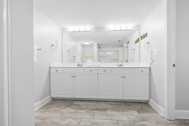 bathroom featuring a shower with curtain, double vanity, baseboards, and a sink
