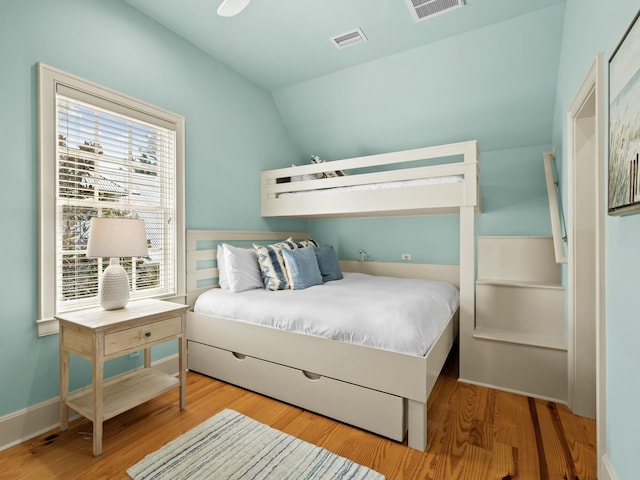bedroom with visible vents, baseboards, vaulted ceiling, and wood finished floors