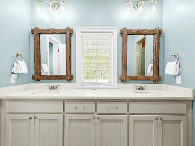 full bathroom with double vanity, a sink, and walk in shower