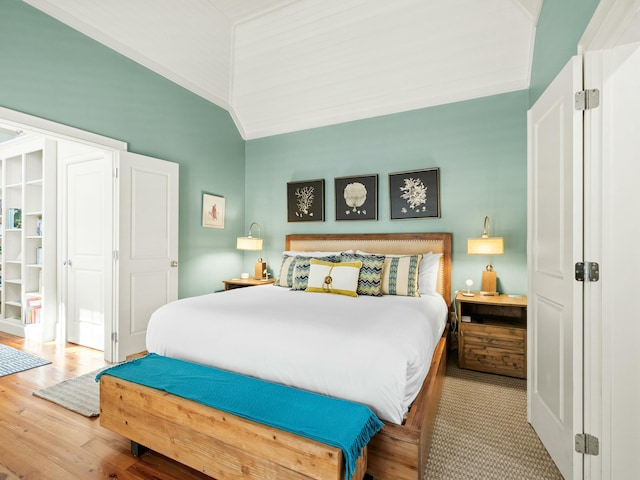 bedroom featuring ornamental molding, wood finished floors, and lofted ceiling