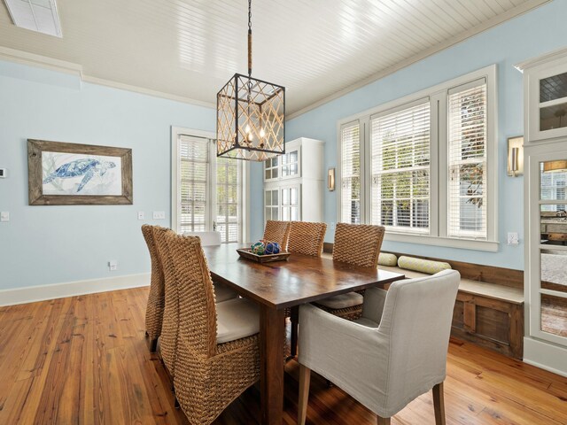 dining area featuring light wood-style floors, an inviting chandelier, baseboards, and ornamental molding