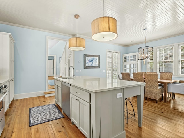 kitchen featuring a breakfast bar, a kitchen island with sink, dishwasher, light countertops, and light wood finished floors