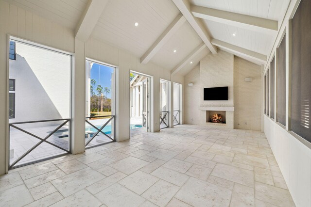 342 Windsong Dr, Inlet Beach, FL 32461 - unfurnished living room with lofted ceiling with beams, stone tile floors, recessed lighting, and a fireplace