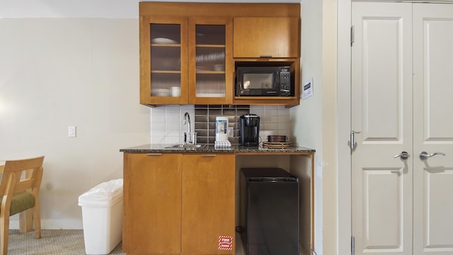 bar featuring black microwave, tasteful backsplash, and a sink