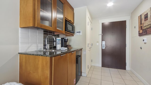 kitchen featuring backsplash, a sink, brown cabinetry, and black microwave