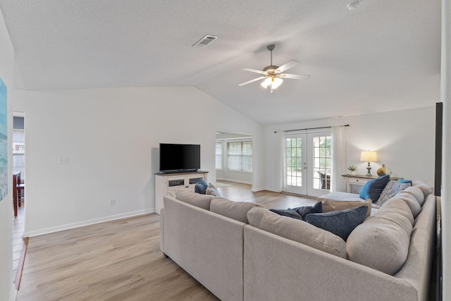 living area with visible vents, light wood-type flooring, vaulted ceiling, french doors, and a ceiling fan