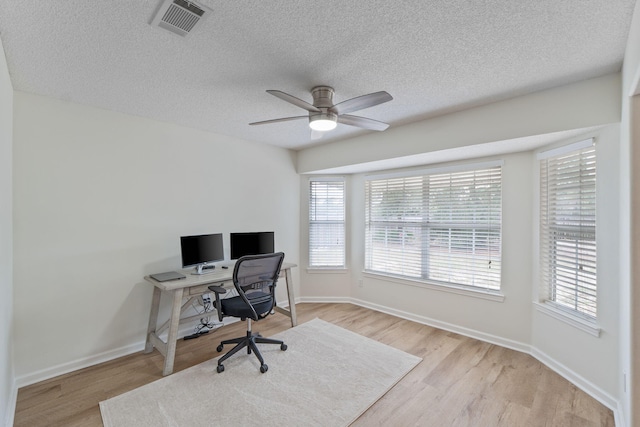 office space featuring ceiling fan, a textured ceiling, visible vents, and light wood-type flooring