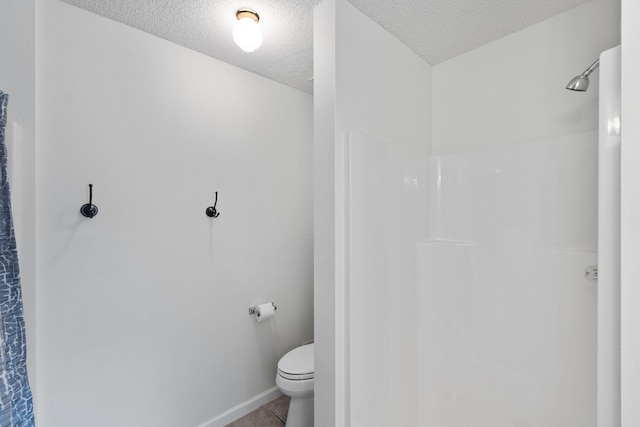 bathroom with walk in shower, tile patterned flooring, toilet, baseboards, and a textured ceiling