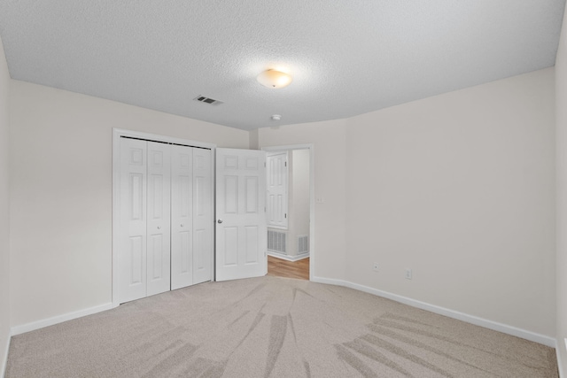 unfurnished bedroom with carpet flooring, a closet, visible vents, baseboards, and a textured ceiling
