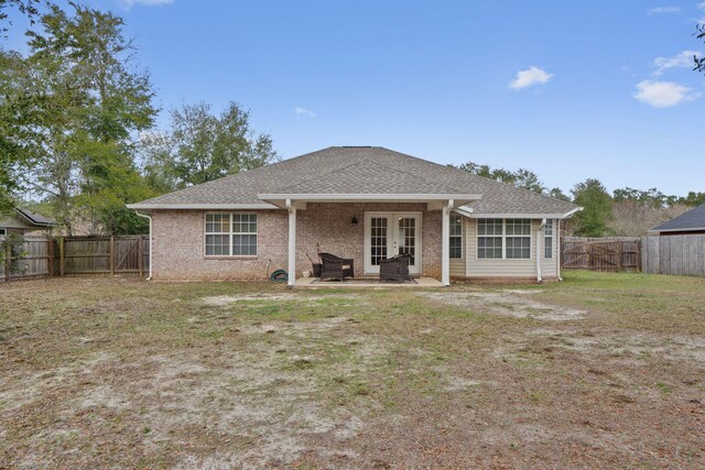 rear view of property with a patio area, roof with shingles, a lawn, french doors, and a fenced backyard