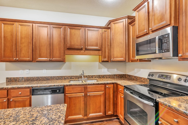 256 Cocobolo Dr, Santa Rosa Beach, FL 32459 - kitchen featuring brown cabinetry, dark stone countertops, stainless steel appliances, and a sink